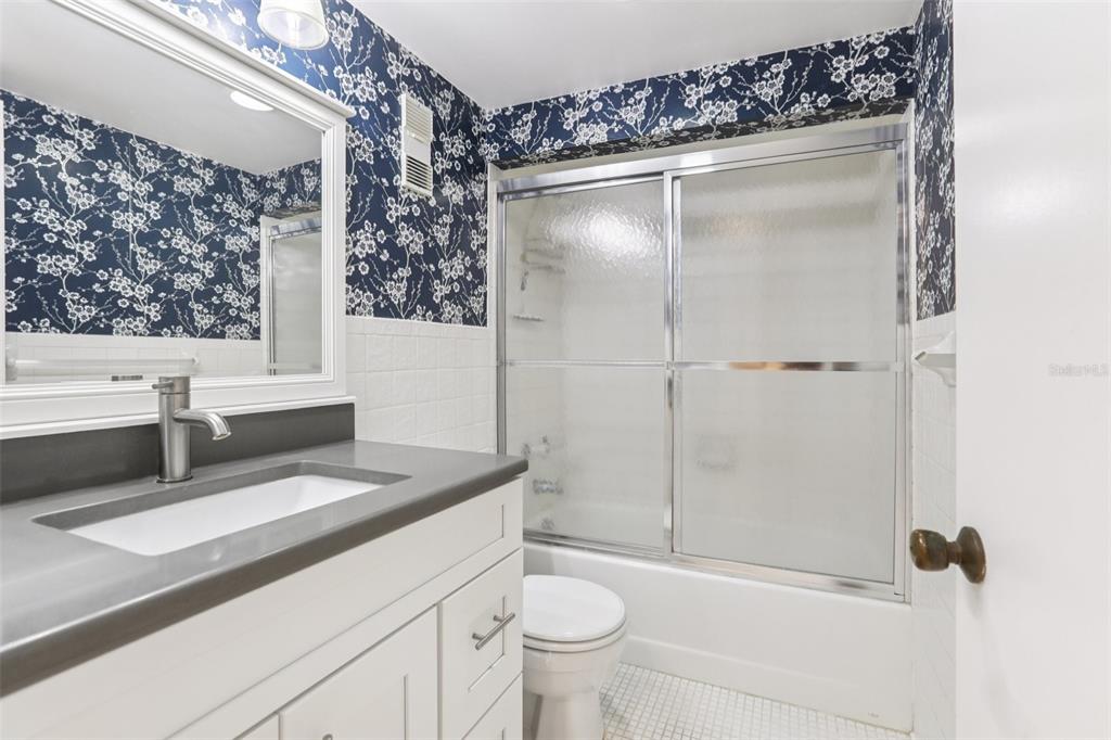 1 Key Capri, Unit 302E Treasure Island, FL 33706 - Photo 18 of 29 a bathroom with a granite countertop sink a toilet and shower