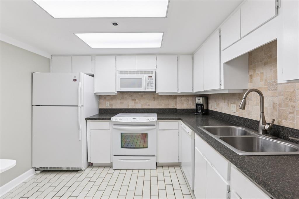 1 Key Capri, Unit 302E Treasure Island, FL 33706 - Photo 9 of 29 a kitchen with stainless steel appliances granite countertop a sink stove and refrigerator