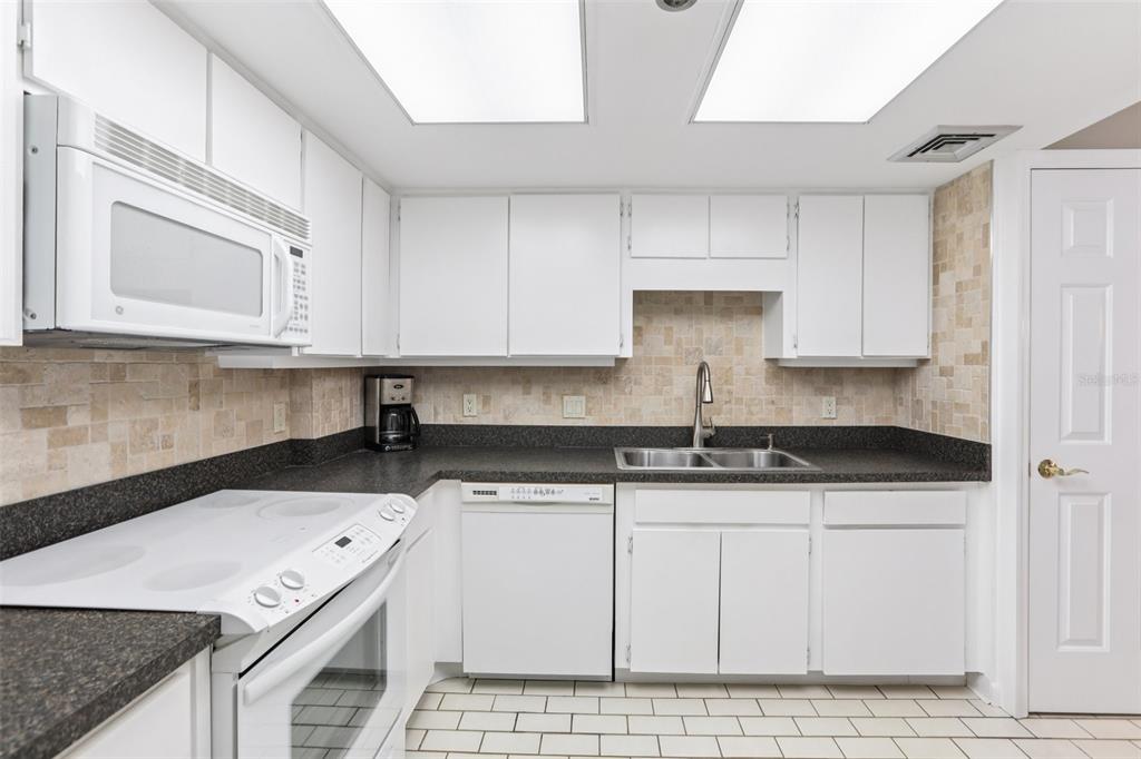 1 Key Capri, Unit 302E Treasure Island, FL 33706 - Photo 10 of 29 a kitchen with granite countertop a sink a stove and cabinets