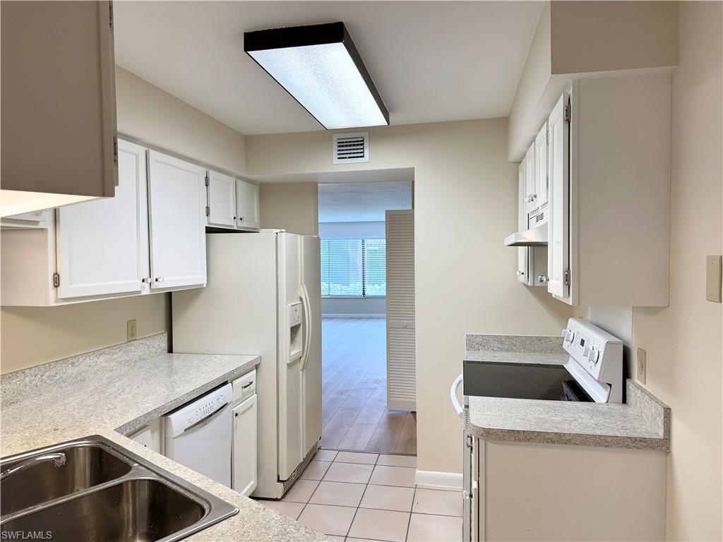 124 Cypress Way East, Unit E3 Naples, FL 34110 - Photo 11 of 22 a kitchen with a sink a refrigerator and cabinets