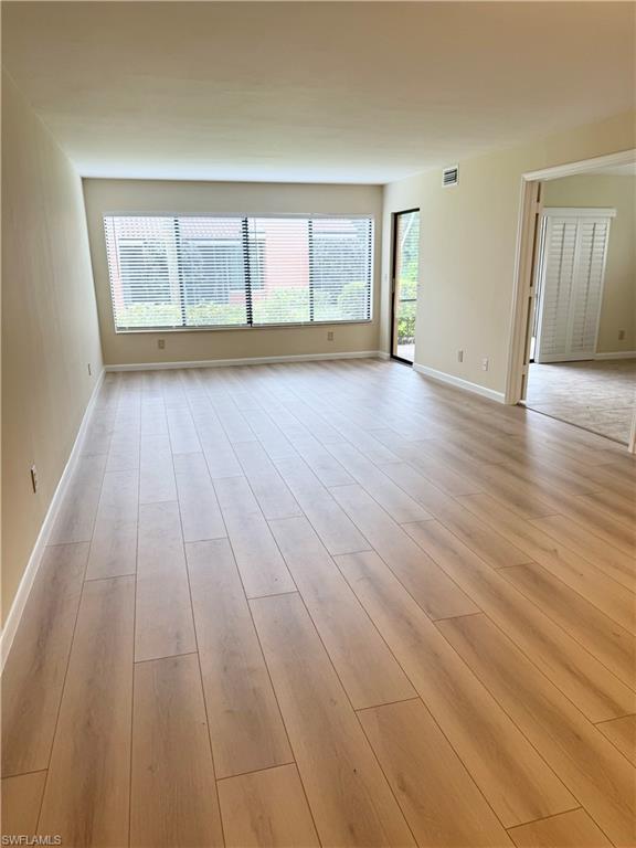 124 Cypress Way East, Unit E3 Naples, FL 34110 - Photo 2 of 22 wooden floor in an empty room with a window