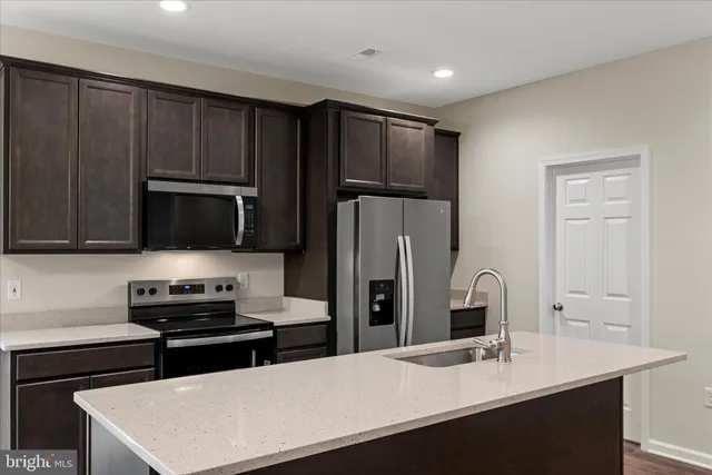 a kitchen with a sink a counter top space cabinets and stainless steel appliances
