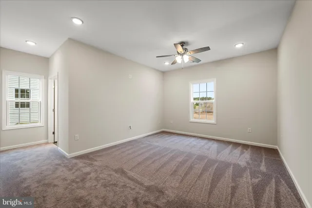 an empty room with windows and ceiling fan