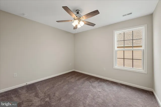 an empty room with window and ceiling fan