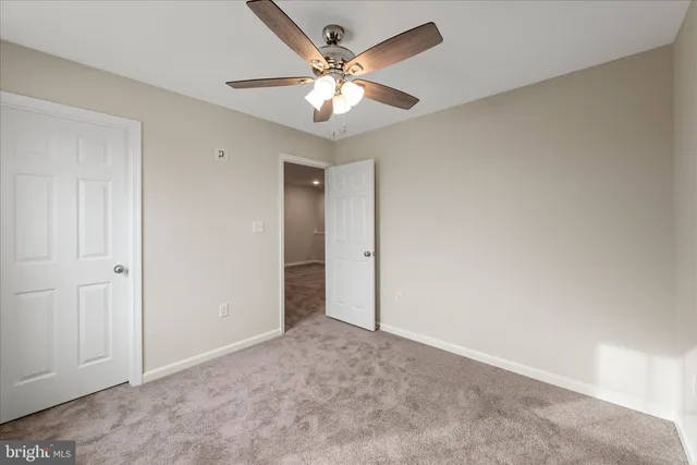 an empty room with closet and a ceiling fan