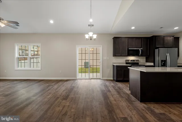 a kitchen with granite countertop a stove a sink dishwasher a refrigerator and a microwave oven with wooden floor