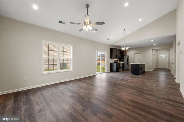 an empty room with wooden floor fireplace and windows