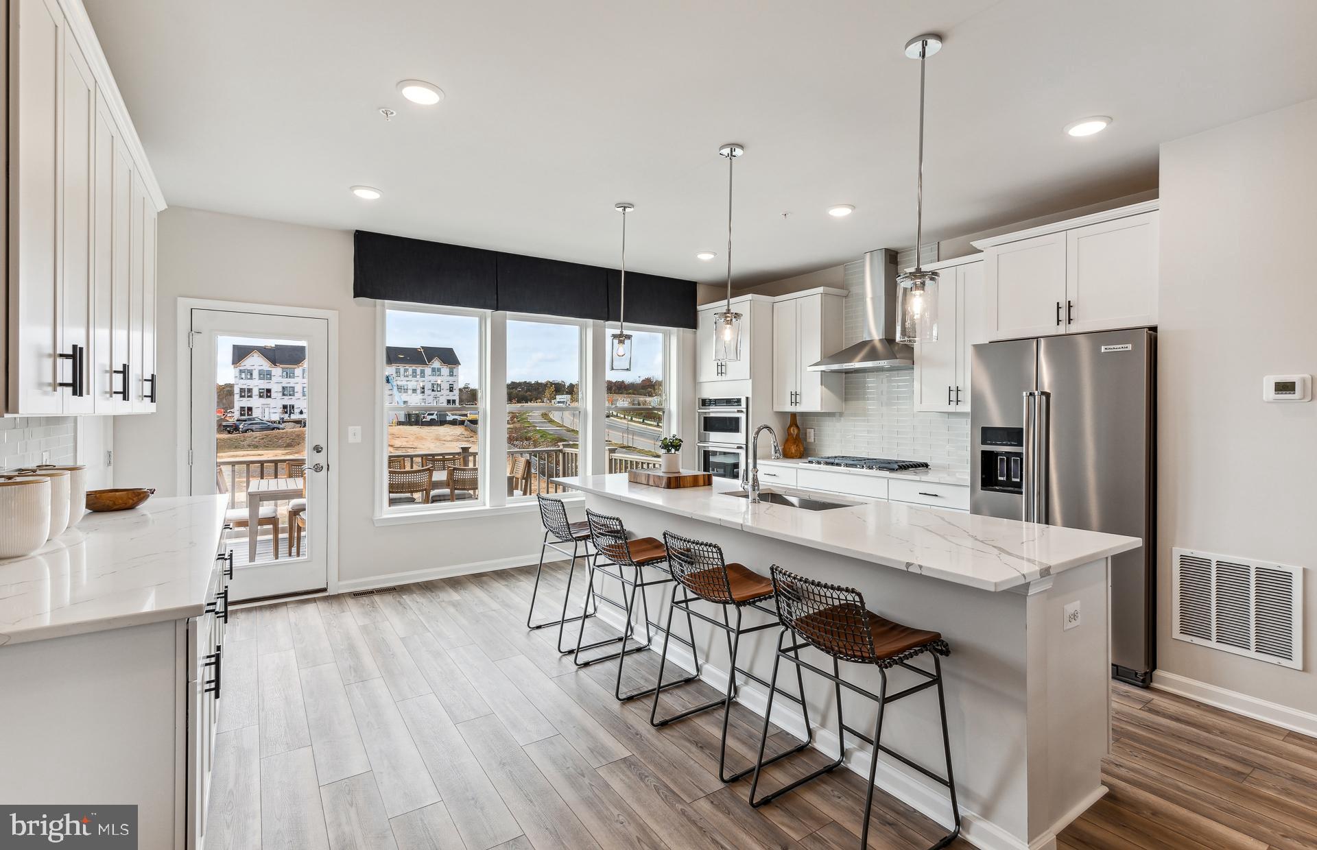 42841 Exeter Spg Terrace Leesburg, VA 20176 - Photo 2 of 38 a kitchen with stainless steel appliances a dining table chairs a sink and a refrigerator