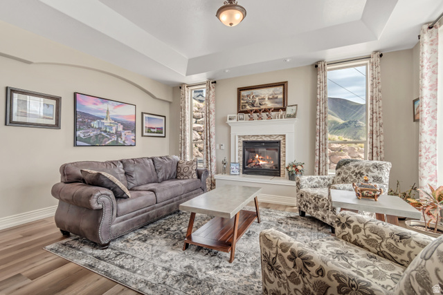 2543 East 700 South Springville, UT 84663 - Photo 17 of 73 Living area with a raised ceiling, a glass covered fireplace, wood finished floors, and a mountain view