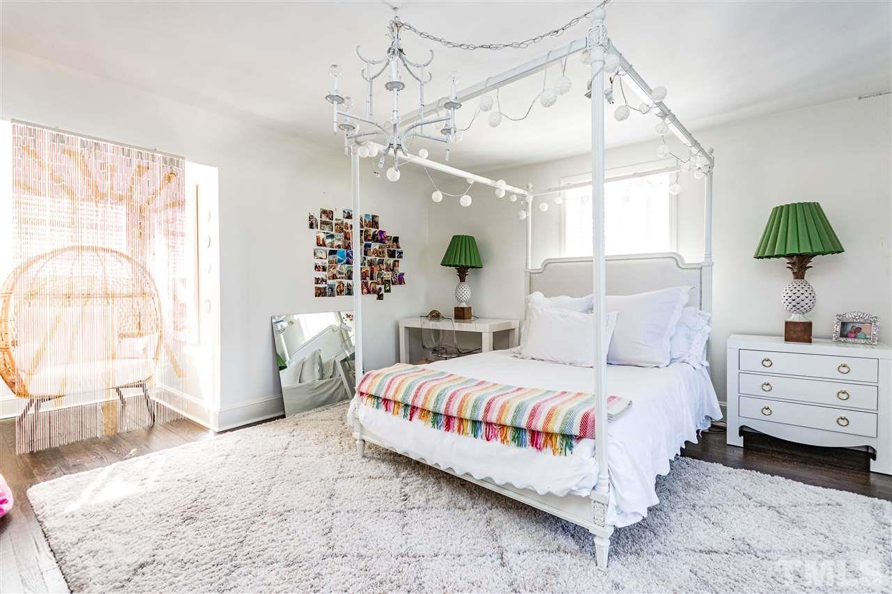 1114 Harvey Street Raleigh, NC 27608 - Photo 20 of 24 a bedroom with a bed chandelier and window