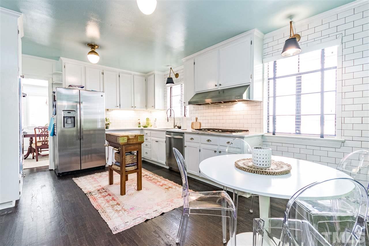 1114 Harvey Street Raleigh, NC 27608 - Photo 7 of 24 a kitchen with stainless steel appliances kitchen island granite countertop a kitchen island hardwood floor sink stove dining table and chairs