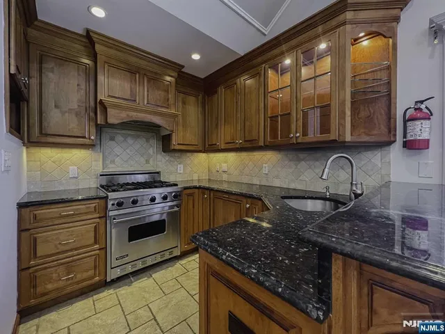 a kitchen with granite countertop a stove sink and cabinets