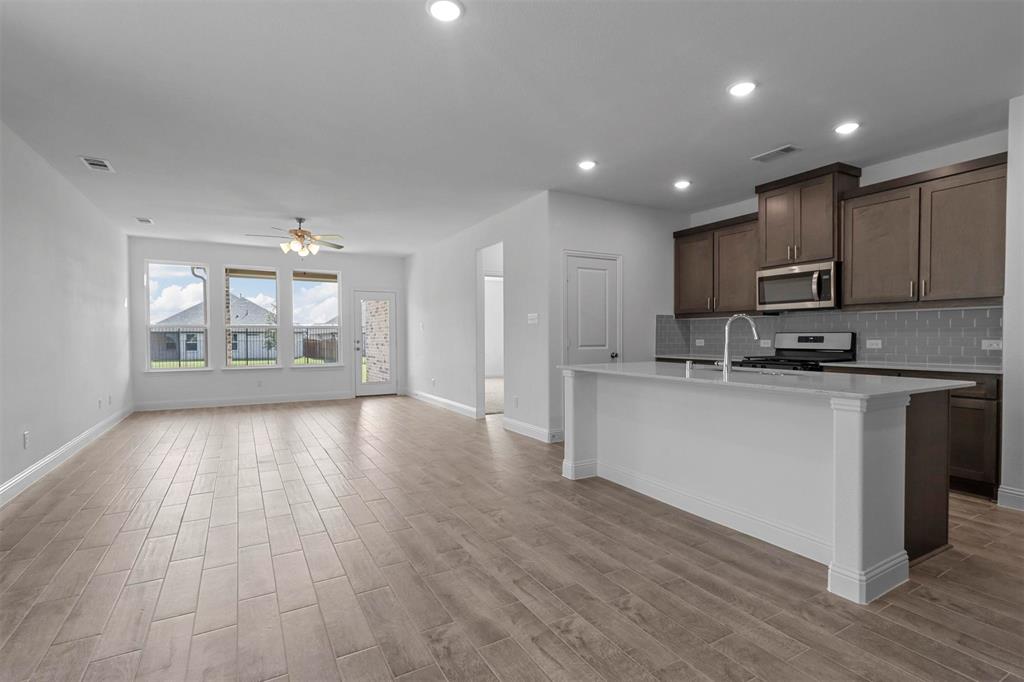 704 Amenduni Lane Anna, TX 75409 - Photo 3 of 19 a open kitchen with kitchen island a sink dishwasher a refrigerator and a stove with wooden floor