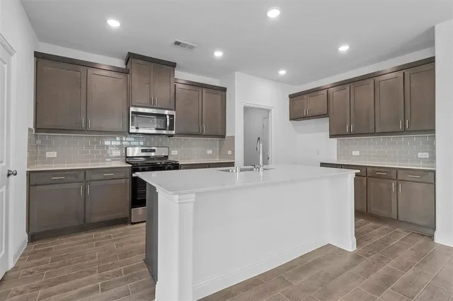 a kitchen with kitchen island granite countertop a sink and stove top oven