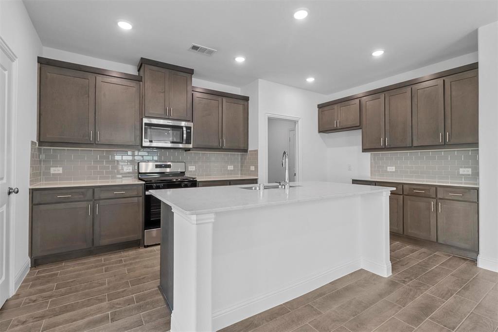 704 Amenduni Lane Anna, TX 75409 - Photo 4 of 19 a kitchen with kitchen island granite countertop a sink and stove top oven