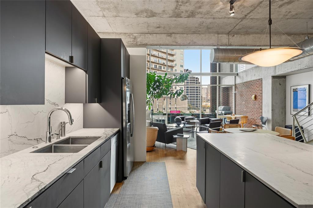 2011 Cedar Springs Road, Unit 305 Dallas, TX 75201 - Photo 7 of 27 Contemporary kitchen featuring dark matte cabinetry, stainless steel appliances, and veined white countertops