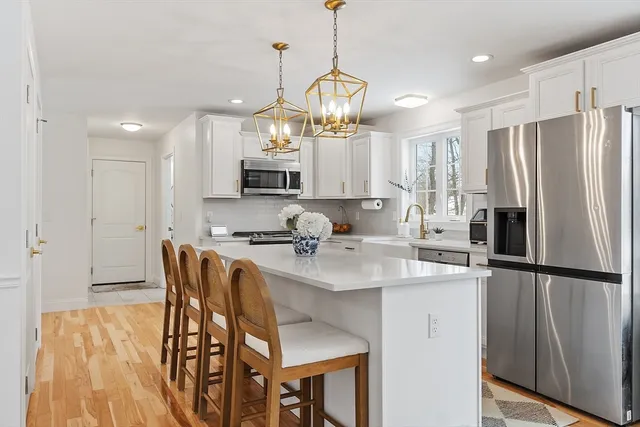 a kitchen with stainless steel appliances a refrigerator a sink a stove a dining table and chairs