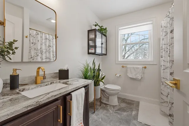 a bathroom with a granite countertop toilet sink and mirror