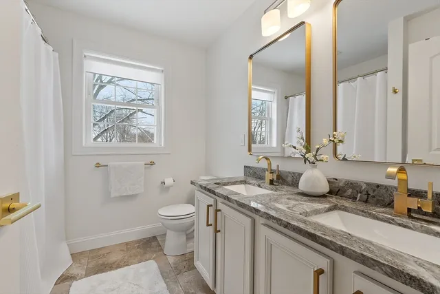 a bathroom with a granite countertop sink mirror and toilet