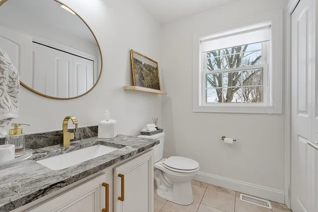 a bathroom with a granite countertop toilet a sink and a mirror