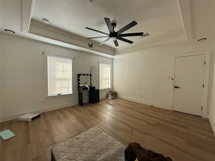 a view of empty room with wooden floor and fan