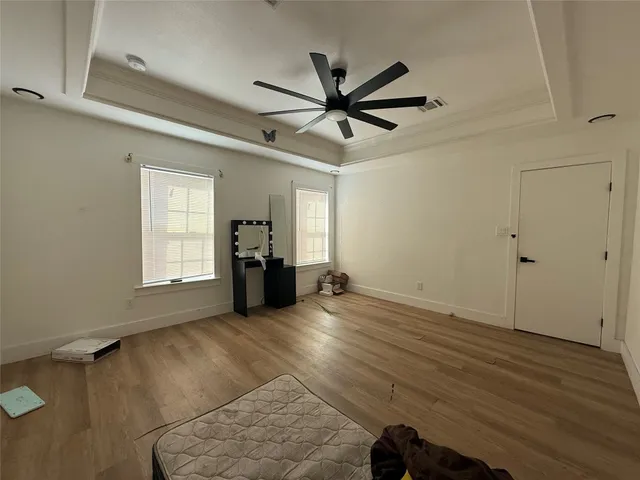 a view of empty room with wooden floor and fan