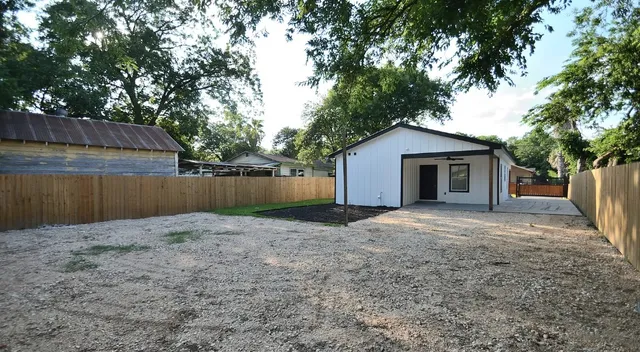 a backyard of a house with a tree and wooden fence
