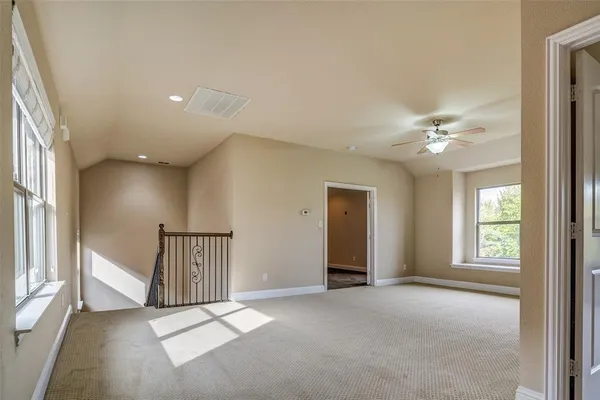 an empty room with windows and chandelier fan