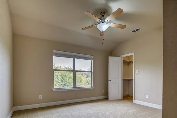 an empty room with windows and ceiling fan