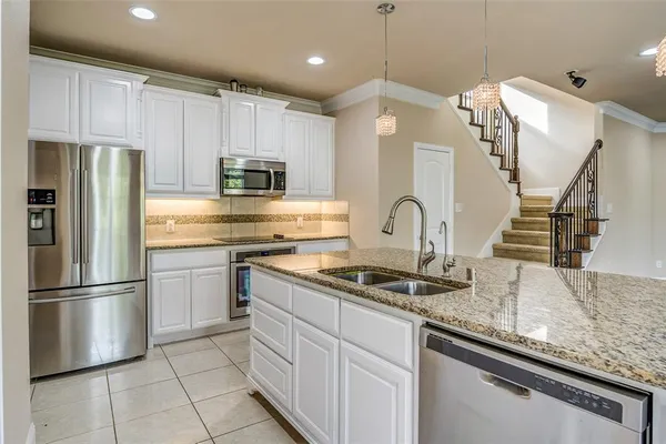 a kitchen with kitchen island granite countertop a sink stainless steel appliances and cabinets