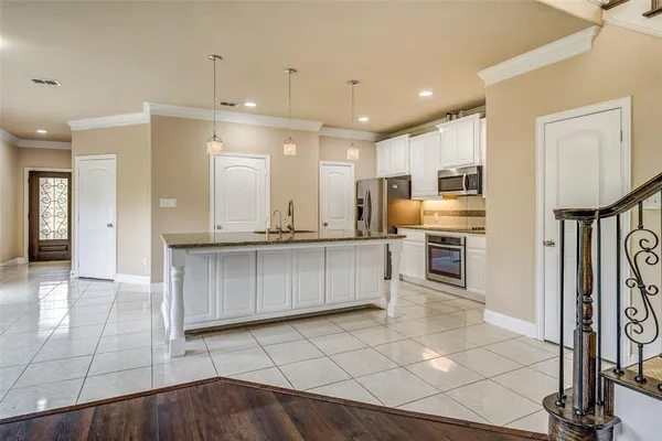a large white kitchen with a sink and dishwasher a stove top oven with wooden floor