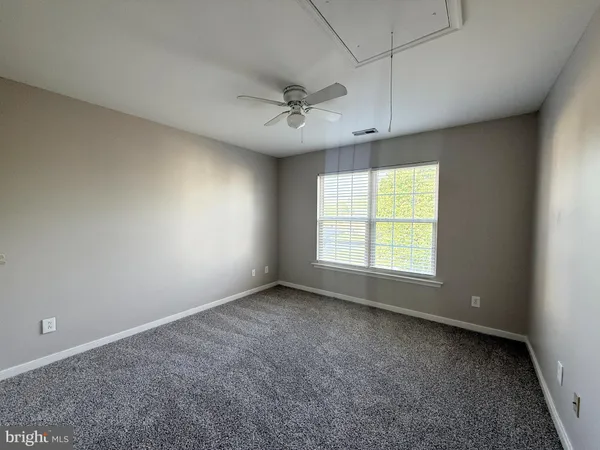 an empty room with windows and ceiling fan