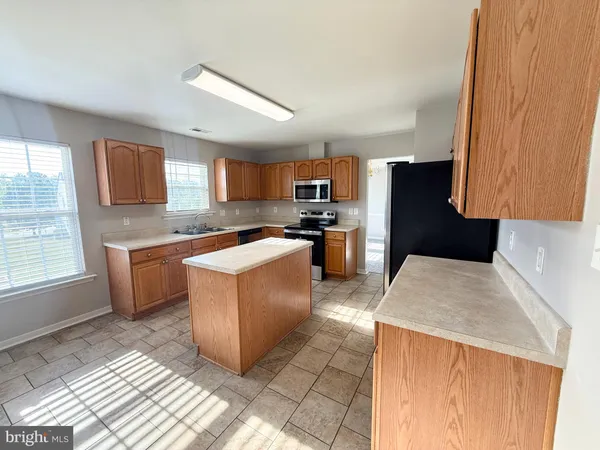 a large kitchen with stainless steel appliances kitchen island granite countertop a stove a sink dishwasher and a refrigerator
