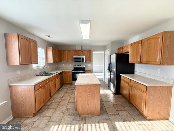 a kitchen with stainless steel appliances granite countertop a stove top oven a sink and a refrigerator