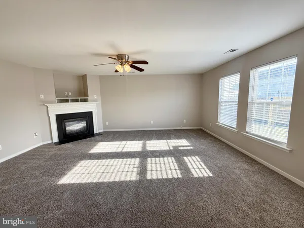 an empty room with windows and fireplace