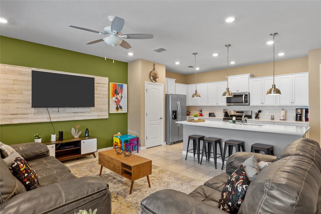 7160 Oakmoss Loop Davenport, FL 33837 - Photo 11 of 45 a living room with stainless steel appliances kitchen island furniture and a flat screen tv