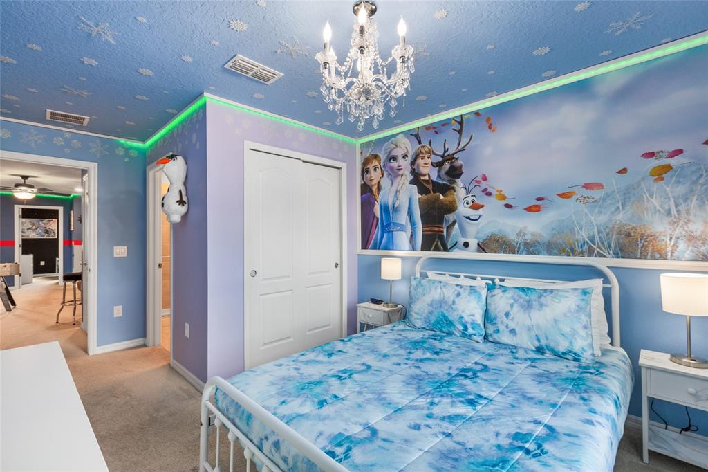 7160 Oakmoss Loop Davenport, FL 33837 - Photo 17 of 45 a bedroom with a bed and a chandelier