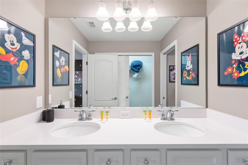 7160 Oakmoss Loop Davenport, FL 33837 - Photo 28 of 45 a bathroom with a sink a mirror and a picture on the wall