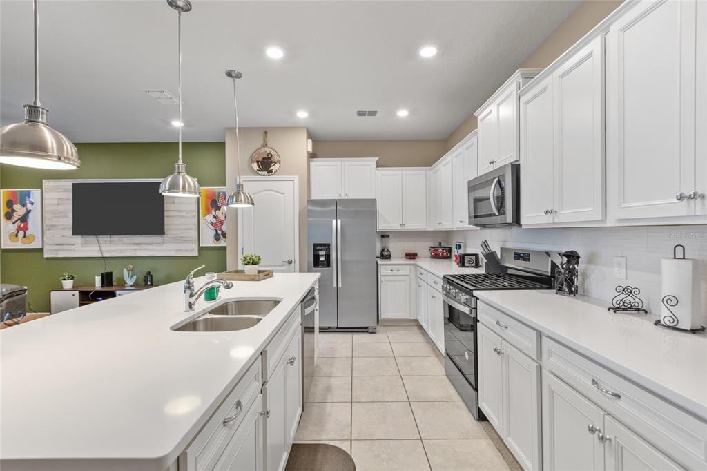 7160 Oakmoss Loop Davenport, FL 33837 - Photo 3 of 45 a kitchen with a sink a counter top space stainless steel appliances and cabinets