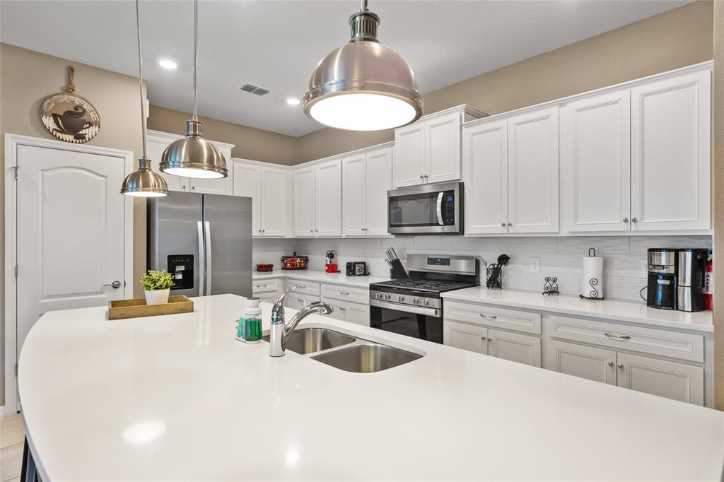 7160 Oakmoss Loop Davenport, FL 33837 - Photo 4 of 45 a kitchen with stainless steel appliances kitchen island granite countertop a sink and cabinets