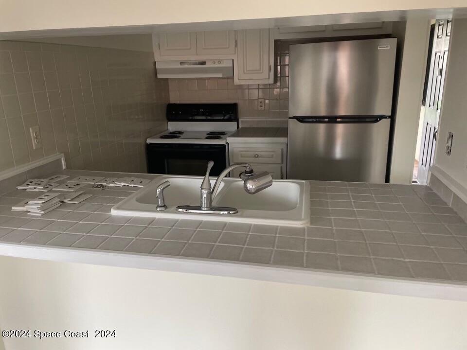 3250 Beach View Way Melbourne Beach, FL 32951 - Photo 3 of 7 a kitchen with a refrigerator a stove and a sink