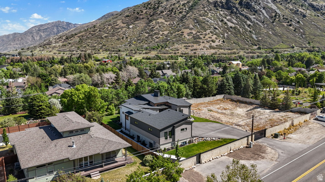 3667 Little Cottonwood Road, Unit 1 Sandy, UT 84092 - Photo 42 of 49 Modern residence featuring a gray and white exterior with a dark shingle roof, surrounded by green landscaping and mature trees, with a mountain backdrop