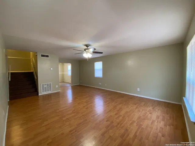 a view of an empty room with wooden floor and a window