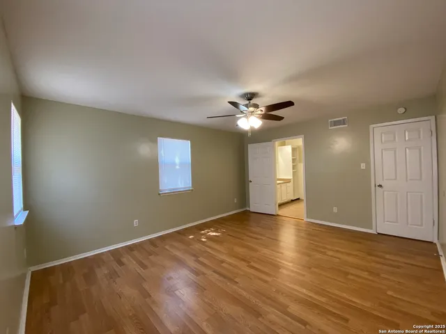 a view of empty room with wooden floor and fan