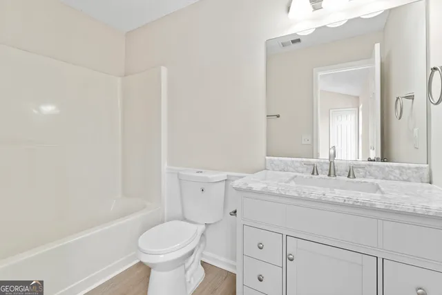a bathroom with a granite countertop toilet sink and mirror