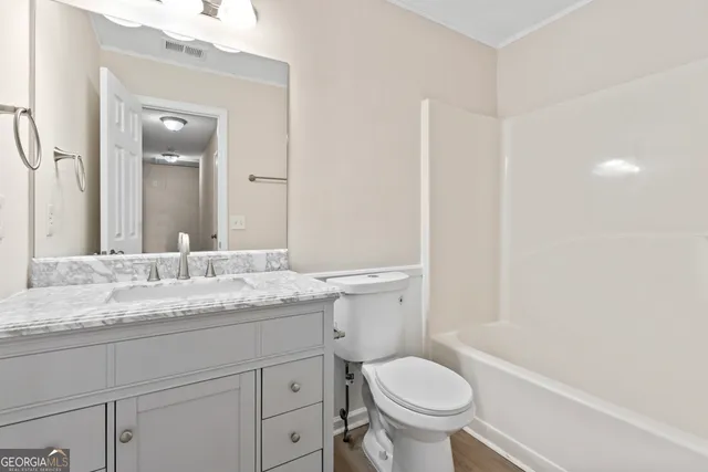 a bathroom with a granite countertop toilet a sink and a mirror