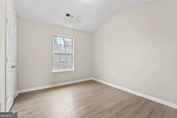an empty room with wooden floor and windows
