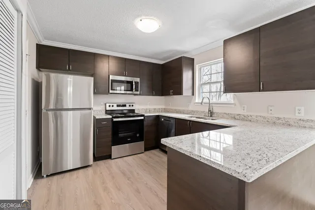 a kitchen with granite countertop a refrigerator stove and sink