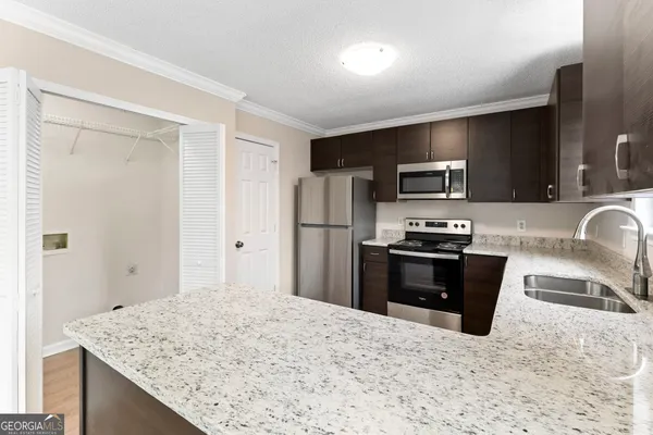 a kitchen with granite countertop a refrigerator stove and sink