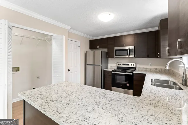 a kitchen with granite countertop a refrigerator stove and sink